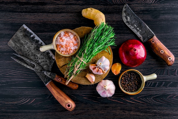 Overhead view of rustic butcher meat knife, cleaver and fork with herbs ans spice on wooden table