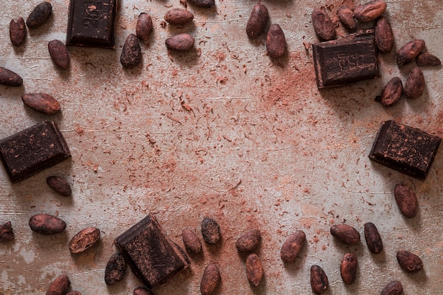 Overhead view of scattered cocoa beans and pieces of chocolate bar