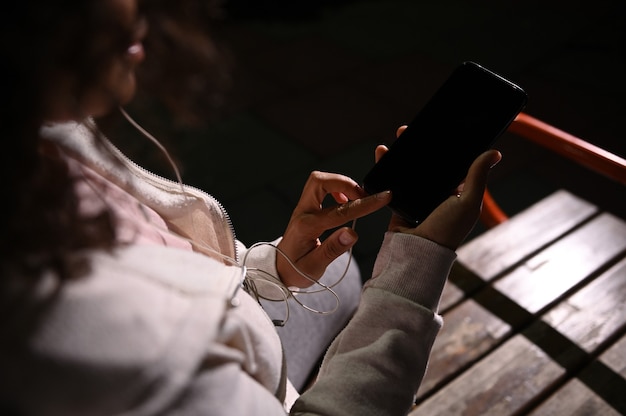 Photo overhead view of a sportswoman holding the mobile phone in her hands and checking mobile application