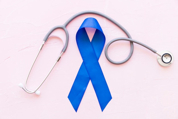 Photo overhead view of stethoscope over the big blue awareness ribbon