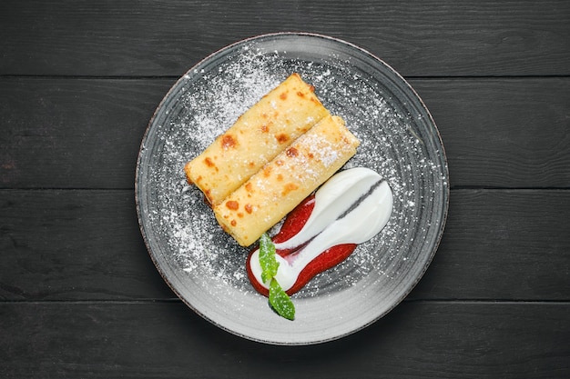 Overhead view of thin crepe with ricotta and strawberry jam on a plate