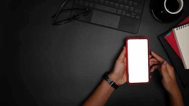 Overhead view woman holding smart phone with white display on black background