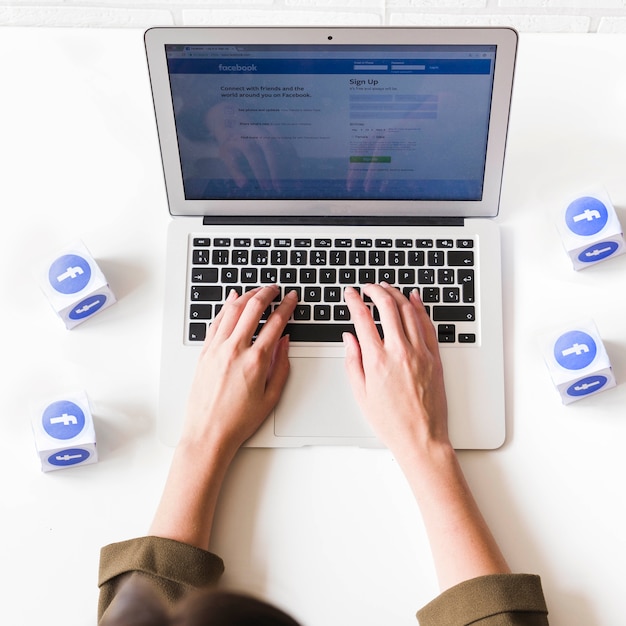 Photo overhead view of woman login into facebook on laptop on white table