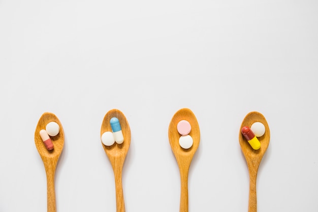 Photo overhead view of wooden spoons with pills isolated on white background