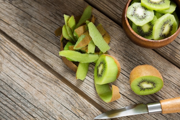 Overheadkosten van plakjes en gepelde kiwi op houten tafel