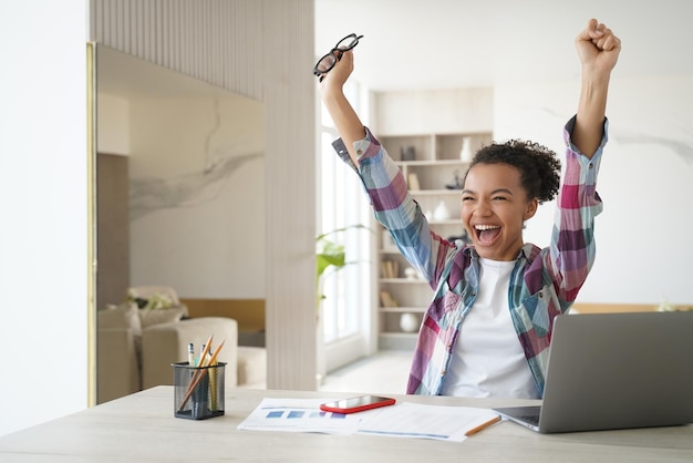 Overjoyed african american student teen girl got email with
good exam scores celebrates success