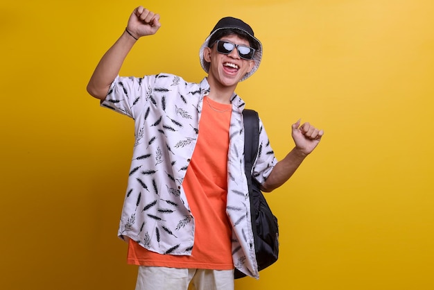 Overjoyed Asian in casual style excited for summer holiday isolated over yellow background