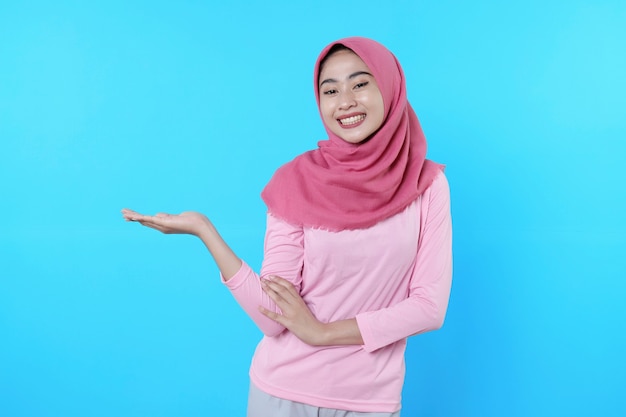 Overjoyed attractive woman shows something on her hand, surprising gesture wearing pink t shirt