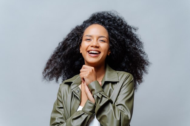 Overjoyed curly woman with luminous hair and casual clothing