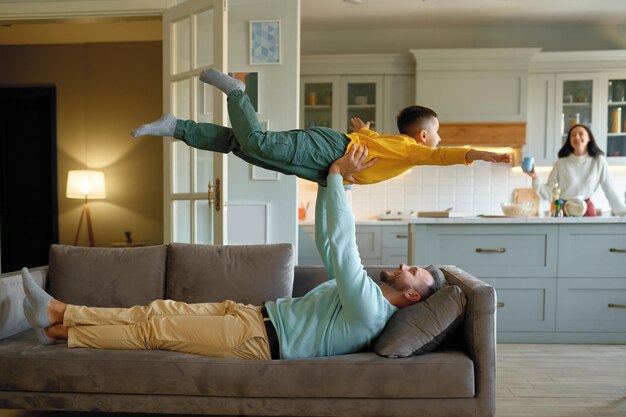 Photo overjoyed father playing with happy excited kid on sofa. loving family spending fun time at home