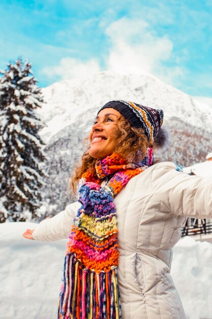 Overjoyed gelukkige jonge vrouw in sneeuw schilderachtige plaats met chalet huis en bomen met bergen in de achtergrond het openen van armen uitstrekken Vrouwelijke mensen en winter vakantie vakantie reis recreatieve activiteit