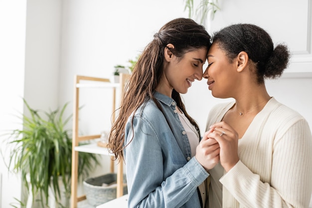 overjoyed and interracial lgbt couple holding hands during engagement