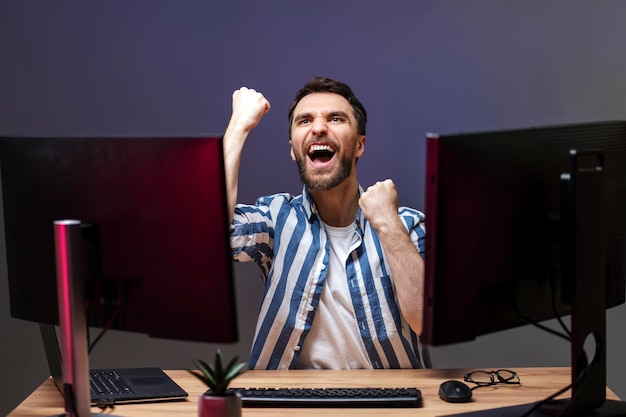 Photo overjoyed man gamer playing computer game at home winning celebration concept