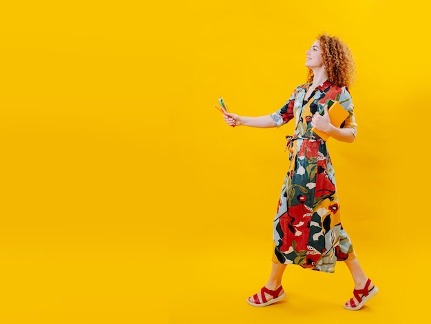 Overjoyed walking young woman holding her notebook and crayons