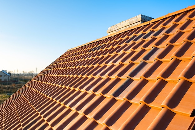 Overlapping rows of yellow ceramic roofing tiles covering residential building roof.