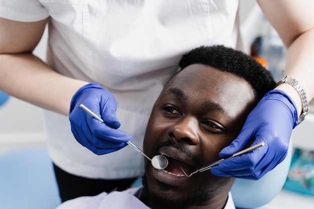 Overleg met tandarts bij tandheelkunde Tandenbehandeling Tandarts onderzoekt afrikaanse man mond en tanden en behandelt tandpijn Afrikaanse man patiënt van tandheelkunde