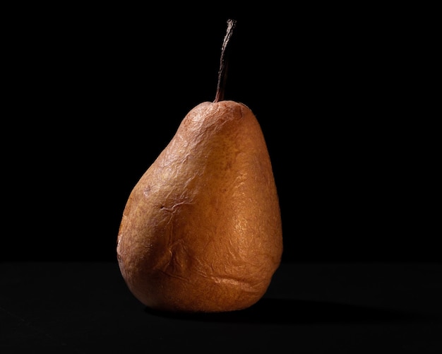 Overripe pear with black background and warm lighting