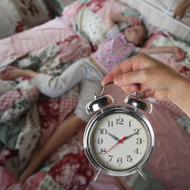 Photo oversleep school hand holds retro alarm clock