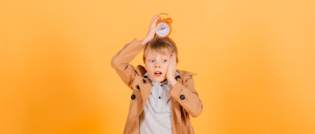 Overslept. Worried awake teen boy with alarm clock is shocked because it is too late