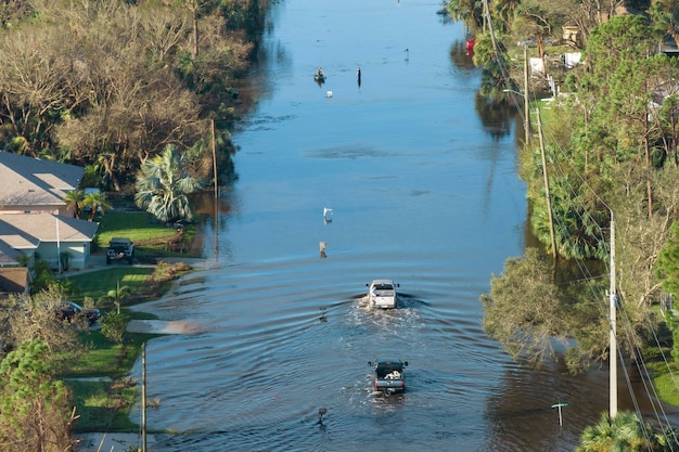 Foto overstroomde florida weg met evacuatie auto's en omringd met water huizen in voorstedelijke woonwijk gevolgen van orkaan natuurramp