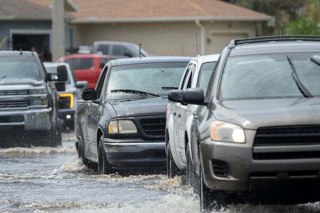 Overstroomde straat na orkaanregen met rijdende auto's in een woonwijk in florida consequenties van een natuurramp