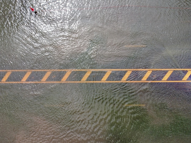 Overstroomde wegen, mensen met auto's die er doorheen rijden. luchtfoto drone-fotografie toont straten die onder water staan en voorbijrijdende auto's van mensen, opspattend water.