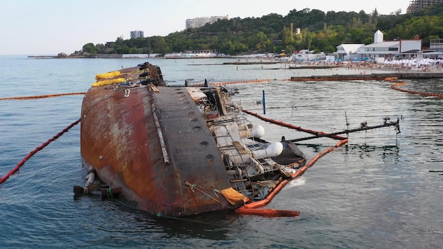 Photo overturned rusty oil tanker ship in the shallow water drowned sunken ship on its edge marine sea sca
