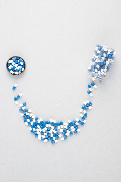 Overview of small jar containing blue-and-white pills forming smile ending in round lid