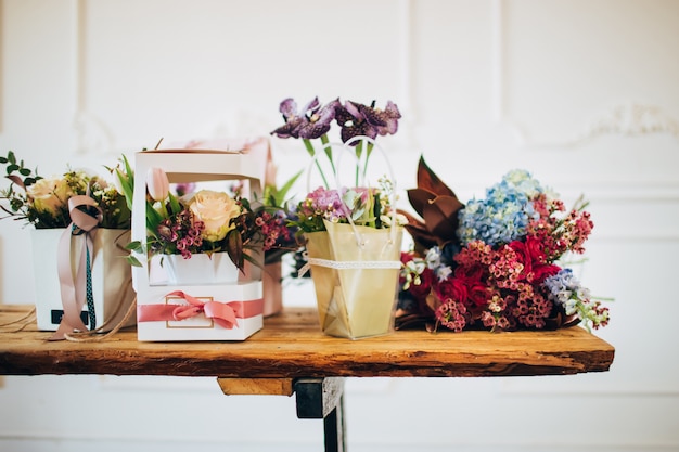 Overvloed aan bloemen. dozen met bloemen staan op een houten tafel. bloemenwinkel. balie in de bloemenwinkel.