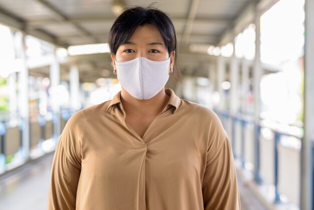 Overweight Asian woman with mask for protection from corona virus outbreak at the footbridge outdoors