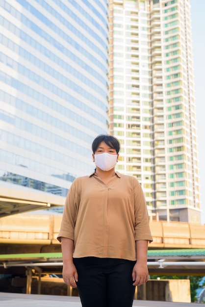 Overweight Asian woman with mask at skywalk bridge