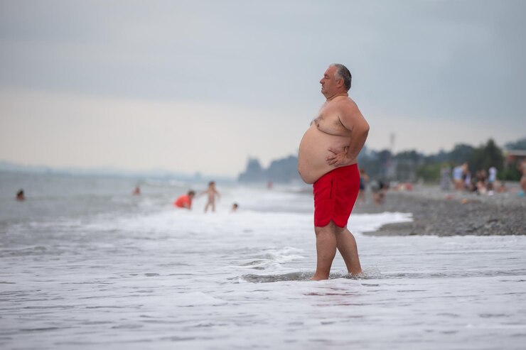 An overweight elderly man is resting on the sea