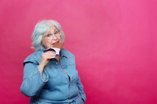 Overweight elderly woman biting into a chocolate bar