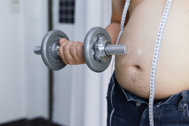 Overweight man exercising by lifting weight with a dumbbell