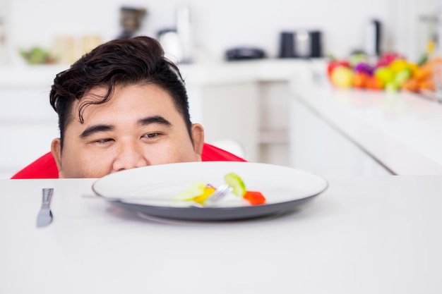 과체중인 남자가 테이블의 샐러드를 엿보고 있다