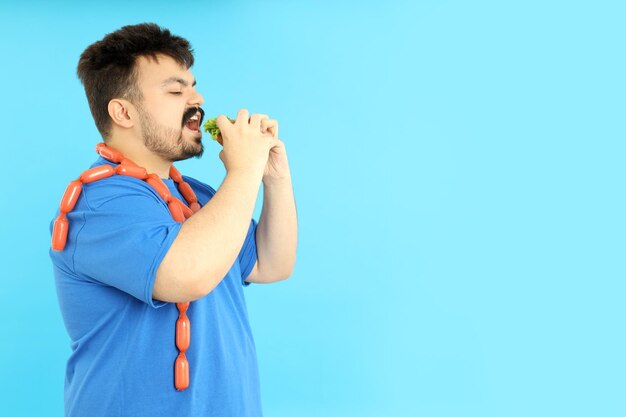 Overweight man with food on a blue background