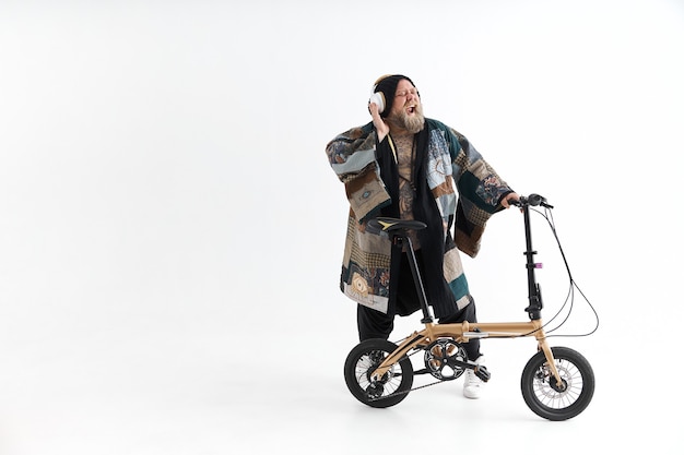 Overweight tattooed man in kimono is holding little bicycle and smilling