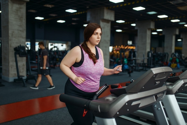 ジムのトレッドミルで運動をしている太りすぎの女性、アクティブなトレーニング。太りすぎの女性は、太りすぎ、肥満に対する有酸素運動、スポーツ クラブに苦しんでいます