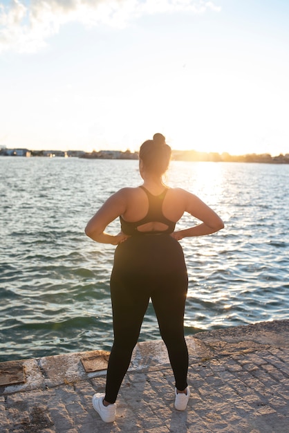 Фото Женщина с избыточным весом тренируется на открытом воздухе у озера