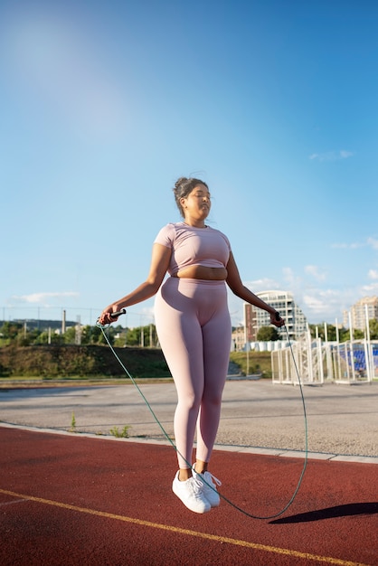 Photo overweight woman exercising with jumping rope outdoors