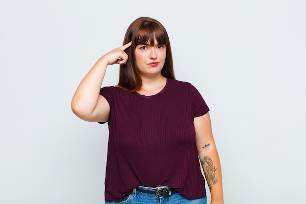 Overweight woman feeling confused and puzzled, showing you are insane, crazy or out of your mind