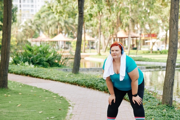 Overweight woman having break after jogging