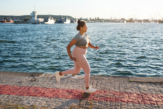 写真 湖のほとりで屋外ジョギングをしている太りすぎの女性