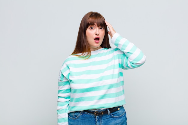 Overweight woman looking happy, astonished and surprised, smiling and realizing amazing and incredible good news