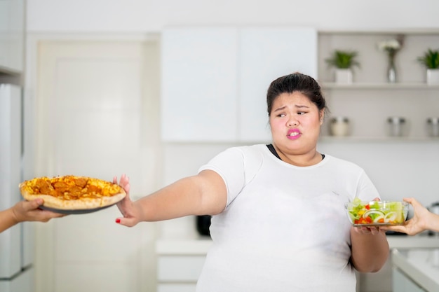 Overweight woman refusing to eat pizza