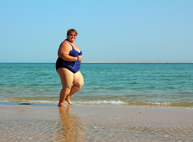 Overweight woman running on beach