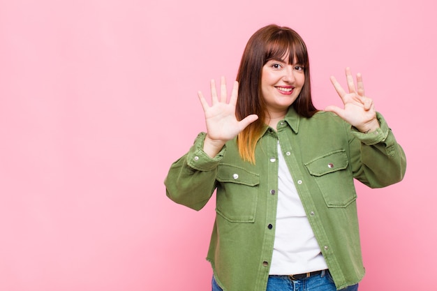 Overweight woman smiling and looking friendly, showing number nine or ninth with hand forward, counting down