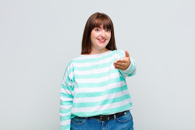 Photo overweight woman smiling, looking happy, confident and friendly, offering a handshake to close a deal, cooperating