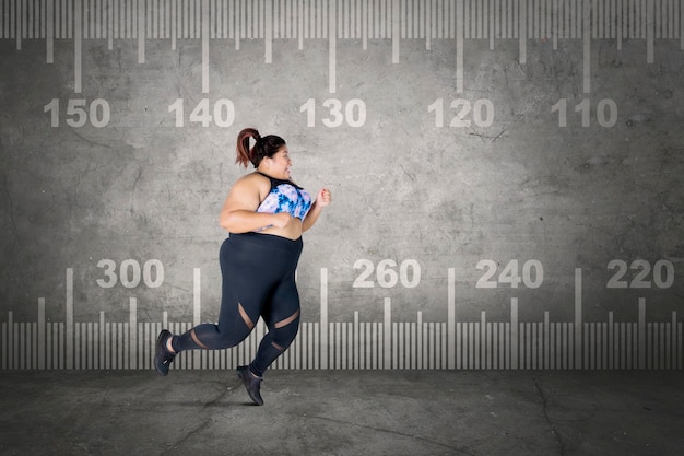 Photo overweight woman sprinting with a measure tape