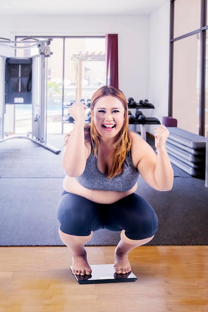 Overweight woman squat down on the weight scales